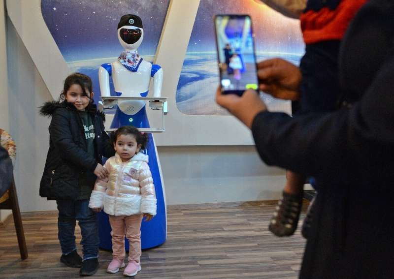 Children pose for a picture next to a robot waiter