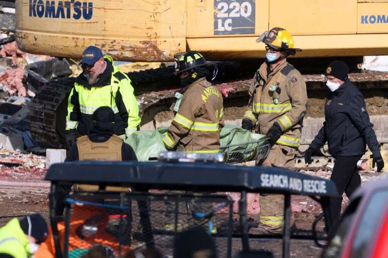 کارگران اورژانس جسد یک قربانی گردباد را در کارخانه شمع سازی محصولات مصرفی در میفیلد پس از نابودی جسد بیرون می آورند.
