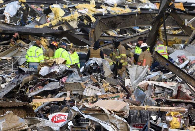 Emergency workers search what is left of the Mayfield Consumer Products Candle Factory after it was destroyed by a tornado in Ma
