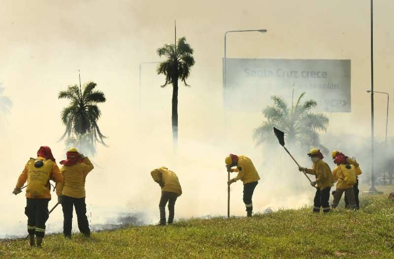 Firefighters try to extinguish a grass fire near the Viru Viru airport in Santa Cruz, Bolivia on August 1, 2021; the department 