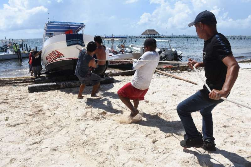 Fishermen and tour operators haul their boats onto dry land as a hurricane approaches Mexico's Caribbean coast