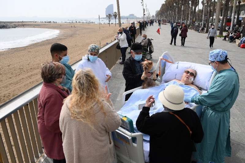 Friends, neighbours and medical personnel surround COVID-19 patient Marta Pascual, 72, as she gets some fresh air at the Barcelo