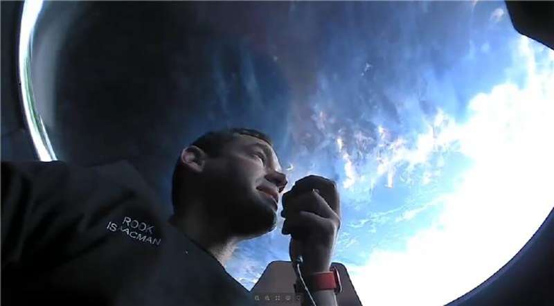 Inspiration4 commander Jared Isaacman communicating while looking out the  observation window on the SpaceX capsule