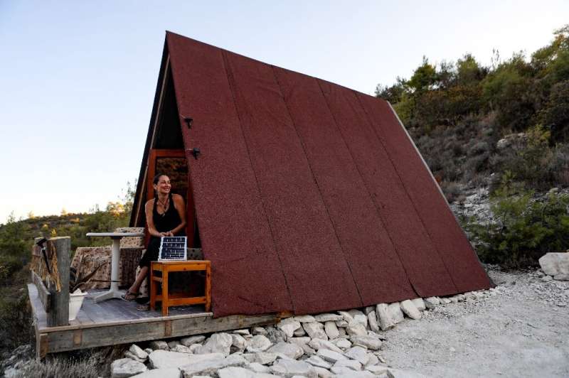Melissa Ahearn sits at the entrance of the A-frame dwelling which she lives in and built with her partner to run exclusively on 