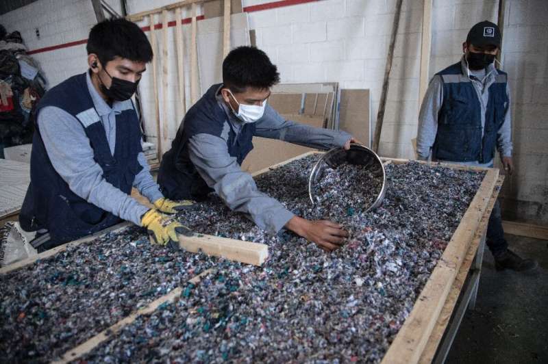 Men work at a factory that recycles used clothes discarded in the Atacama desert for housing insulation panels, in Alto Hospicio