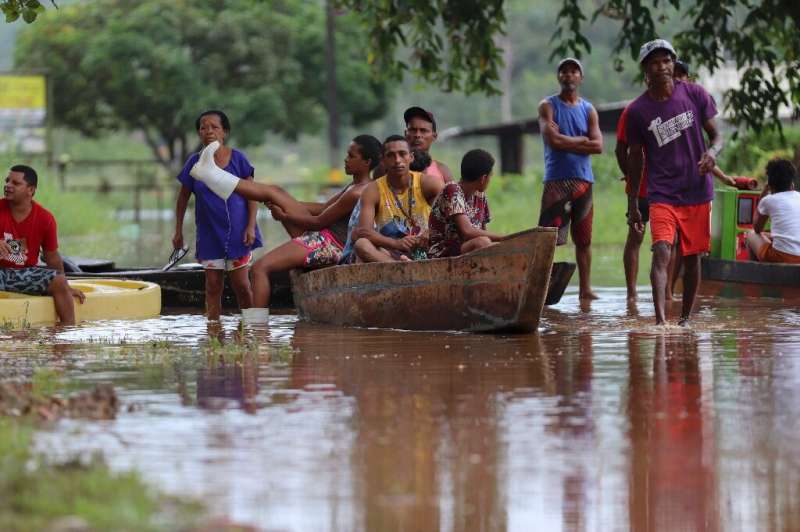 People in the Joia do Atlantico village in Bahia state have to use a boat to cross roads following heavy flooding