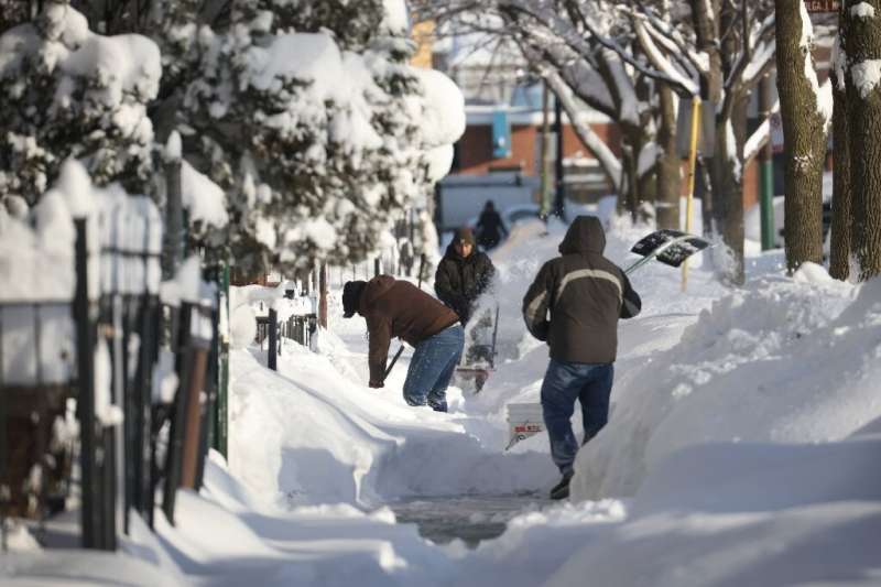 Residents clear snow from a sidewalk on February 16, 2021 in Chicago, Illinois