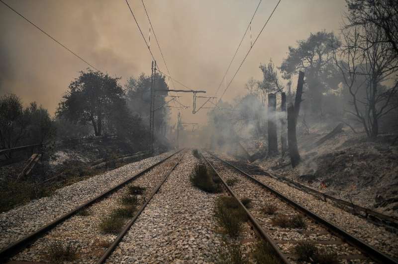 Smoke hovers above a railway as a fire spreads in the village of Afidnes, some 30 kilometres north of Athens