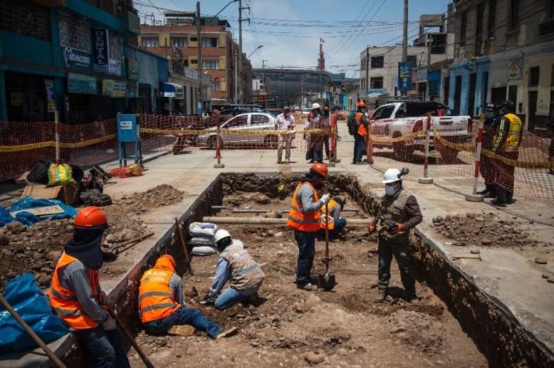 Specialists work around the ancient burial site found by a crew laying a natural gas pipe under a street in Lima, Peru on Novemb