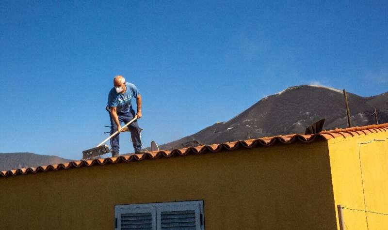 61 year-old mason Felix Rodriguez Luis removes ash from the roof of his house months after the Cumbre Vieja volcano's eruption
