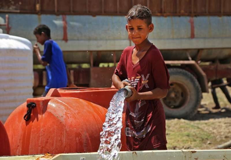 A boy collects water amid shortages and soaring temperature in the Iraqi village of al-Aghawat: dozens of villages depend on spo