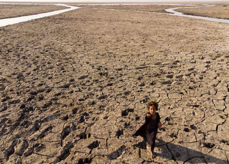 Ребенок в Ираке, стране, сильно пострадавшей от изменения климата и нехватки воды, в высохшем русле отступающего юга Ирака.