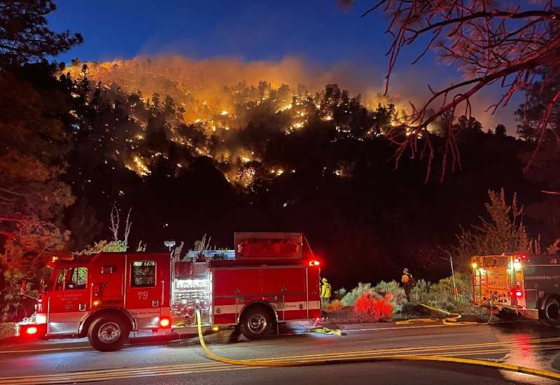 A handout photo courtesy of the San Bernardino County Fire Department shows crews battling a fast-moving brush fire in Wrightwoo