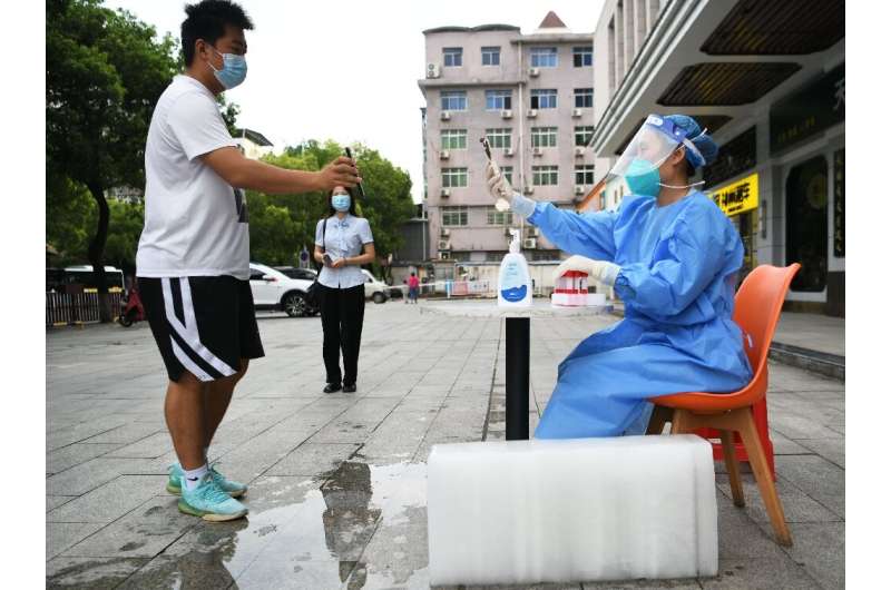 A health worker preparing Covid tests sits next to a block of ice in an attempt to cool off as China bakes under record temperat