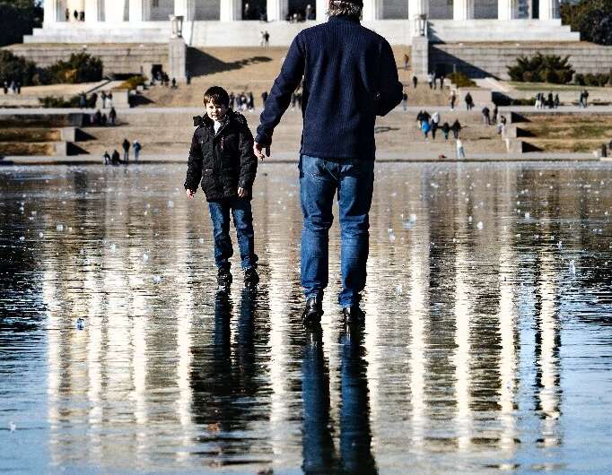 A man and a boy walk across the frozen Reflecting Pool toward the Lincoln Memorial in Washington
