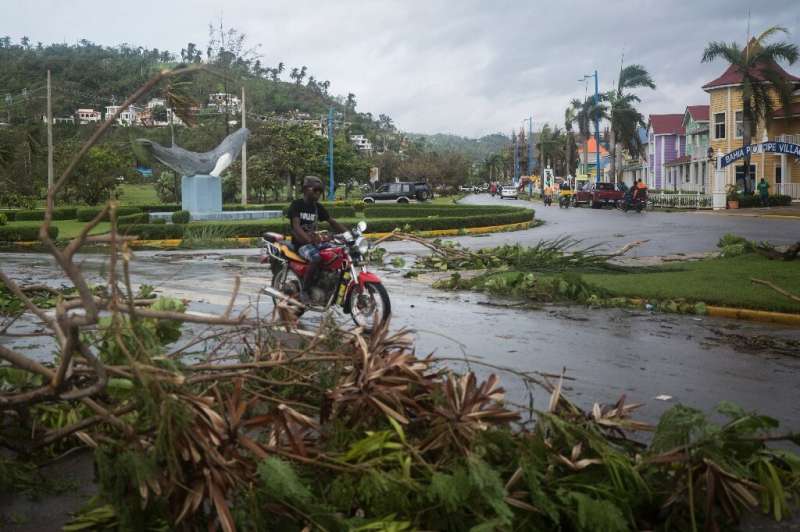 A man rides his motorcycle past fallen branches after Hurricane Fiona in Samana, Dominican Republic