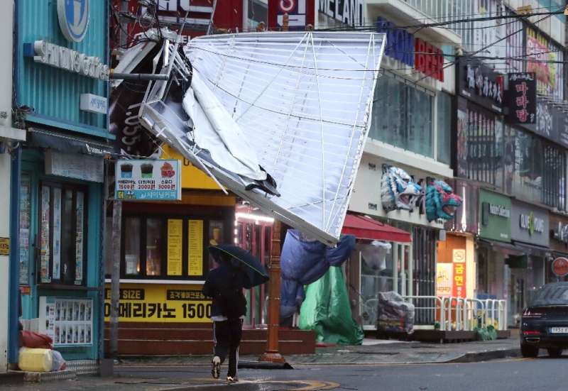 A man walks under the wreckage of a damaged signboard on a shopping street in Changwon, South Korea on Tuesday