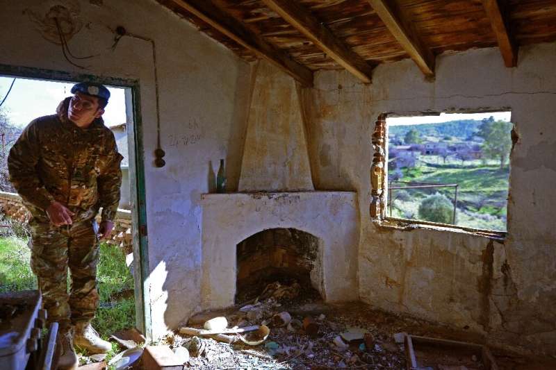 A member of the United Nations Peacekeeping Force in Cyprus inspects a dilapidated house in the abandoned village
