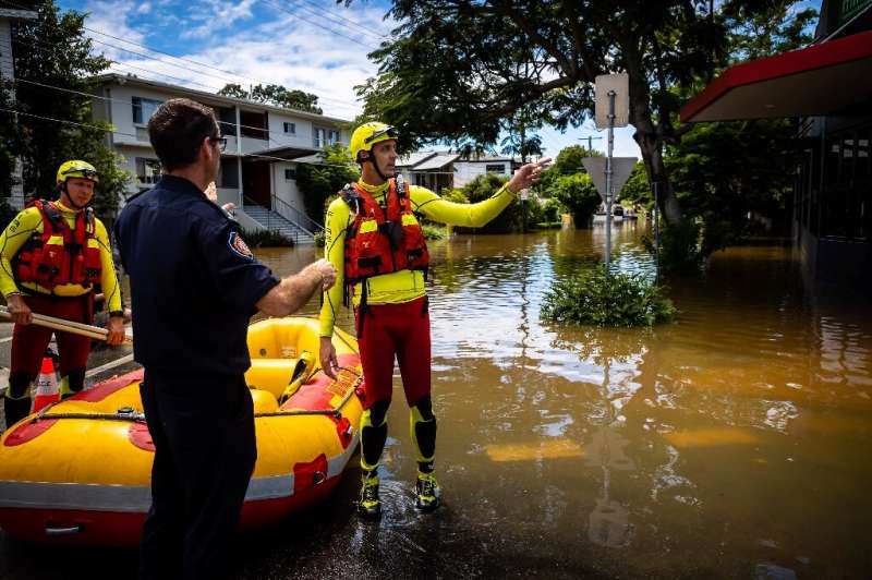 A Queensland Fire and Rescue crew move through the flooded streets of Paddington in suburban Brisbane