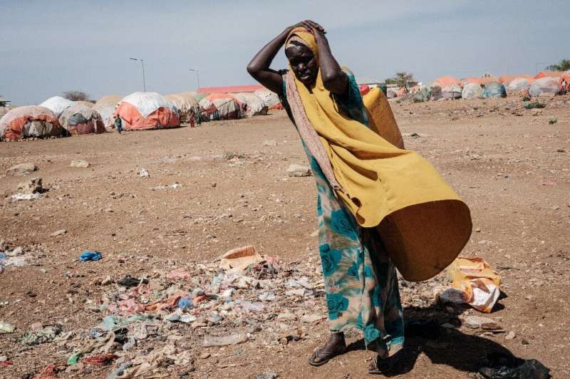 Una mujer carga un recipiente con agua en un campamento para personas desplazadas en Somalia.  Los años de sequía del país resuenan con los