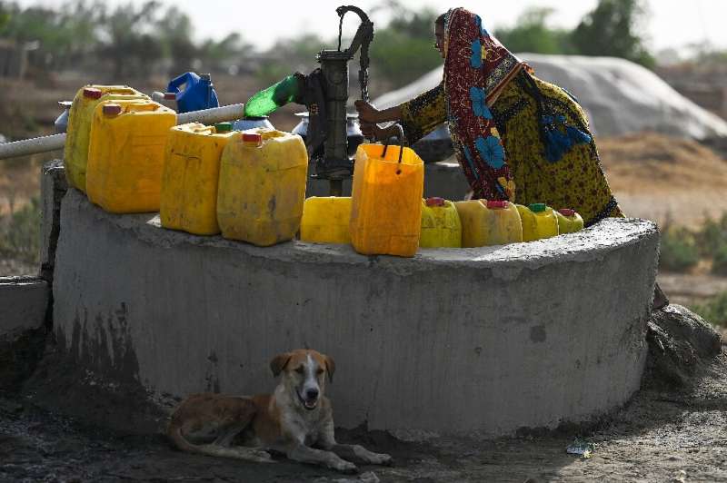 A woman fills containers with water from a hand pump during a heatwave in Jacobabad
