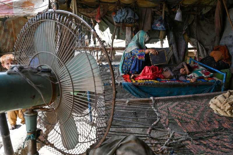 A woman uses a paper sheet to fan her child amid a power cut during a heatwave in the Pakistani city of Jacobabad in May