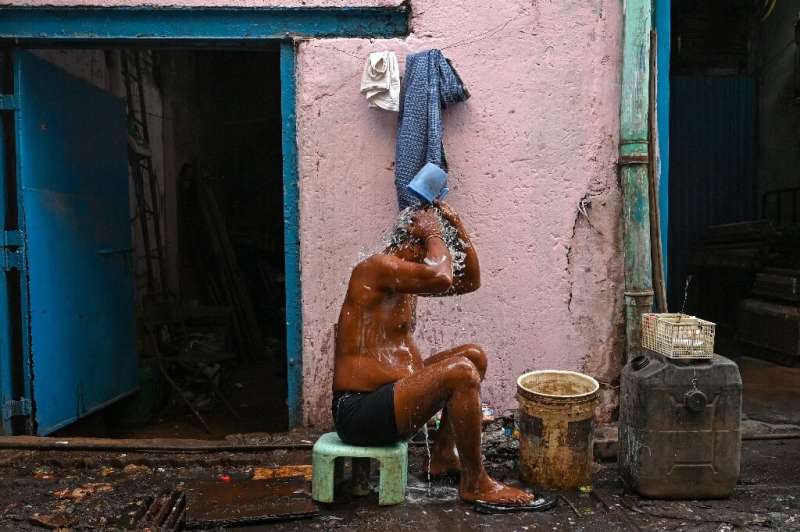 A worker bathes outside a factory in the Dharavi slums of Mumbai, where water and waste management infrastructure have not kept 