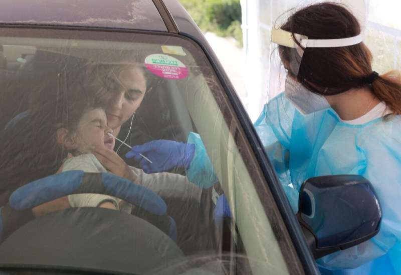 An Israeli paramedic collects a swab sample from a child at the Magen David Adom (Red Shield of David) Covid-19 coronavirus test