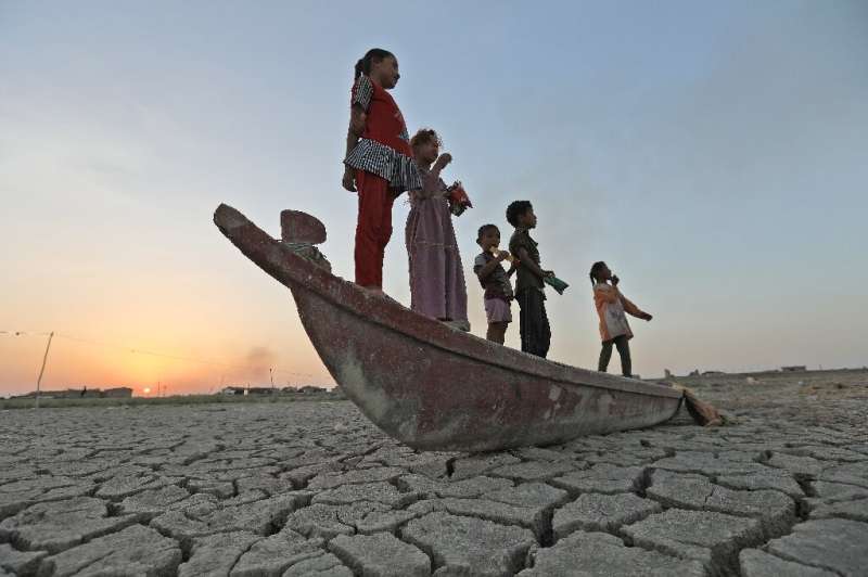 Children stand on a boat lying on the dried-up bed of southern Iraq's receding Chibayish Marshes