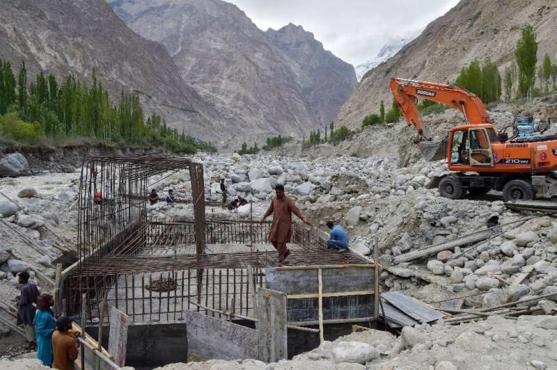 Construction workers build a temporary bridge in Hassanabad after the village's main bridge was destroyed in the flood
