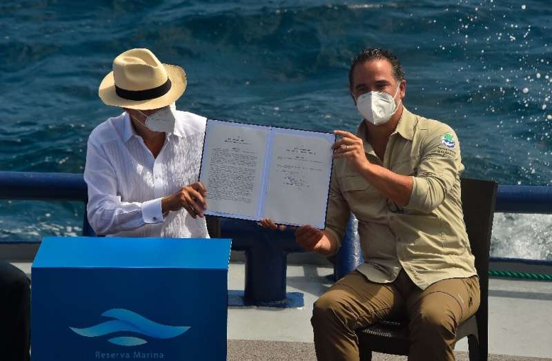 Ecuador's President Guillermo Lasso (L) and Environment Minister Gustavo Manrique show the decree for the expansion of the Galap