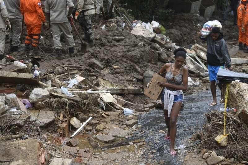 Especialistas dizem que tempestades mortais no Brasil, como a de Petrópolis (pessoas carregam seus pertences em 19 de fevereiro de 2022, após um gi