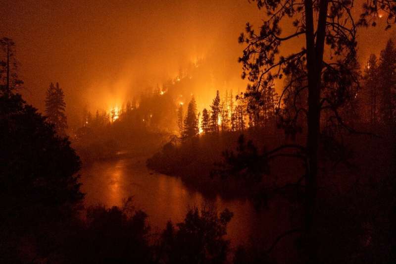Flames burn to the Klamath River during the McKinney Fire in the Klamath National Forest northwest of Yreka, California