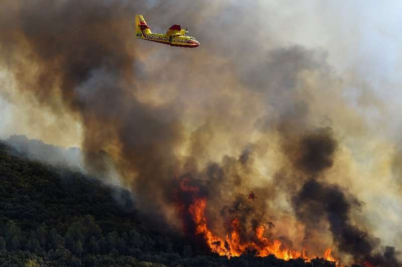 French fire-fighting aircraft fly over burning forests near Gignac, southern France on July 26, 2022 as the country endured a dr