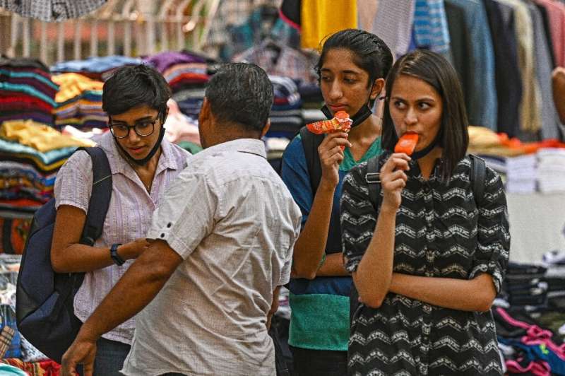 Girls eat ice lollies while shopping on a hot summer afternoon in New Delhi