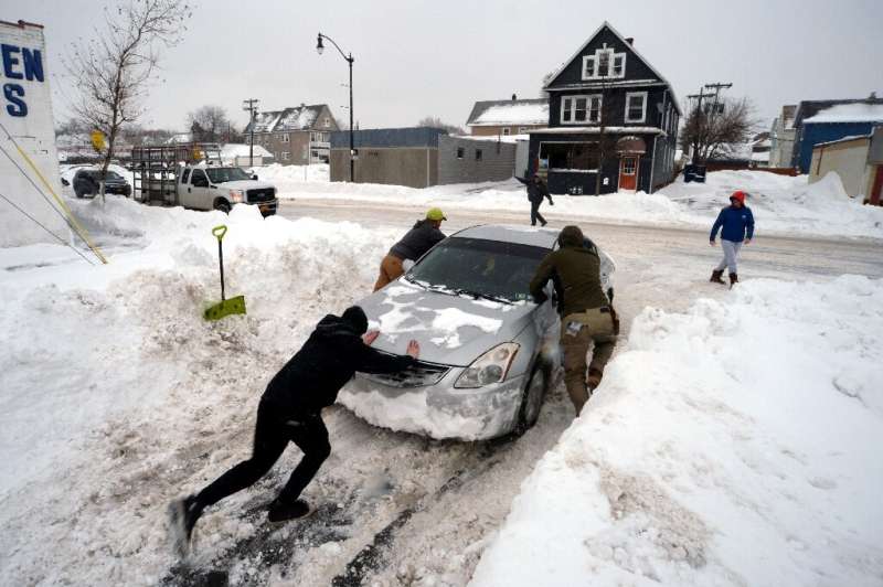 Good Samaritans help to push a car on South Park Avenue in Buffalo, New York