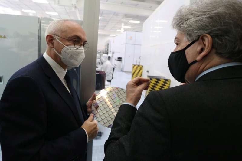 IMEC chief executive officer Luc Van den Hove (L) holds a wafer as he speaks with European Commissioner for Internal Market Thie