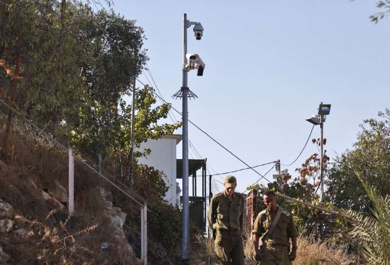 In this file photo taken on November 9, 2021, Israeli soldiers walk past surveillance cameras in the flashpoint Palestinian city