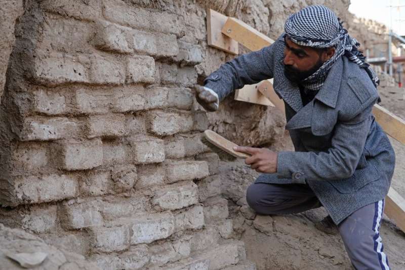 Arqueólogos e trabalhadores iraquianos usam tijolos de barro feitos tradicionalmente para restaurar o templo branco de Anu no local de Warka, no Iraque