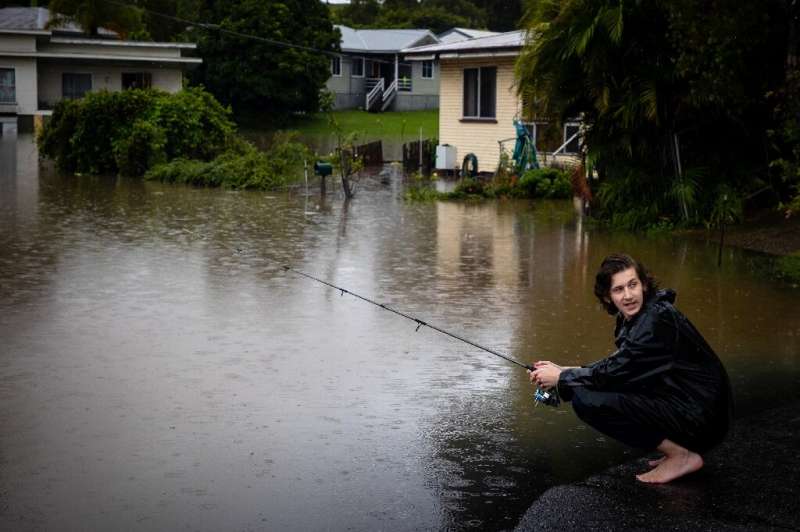 Jai Connors fishes in rising floodwater from the swollen Bremer river in West Ipswich, Queensland