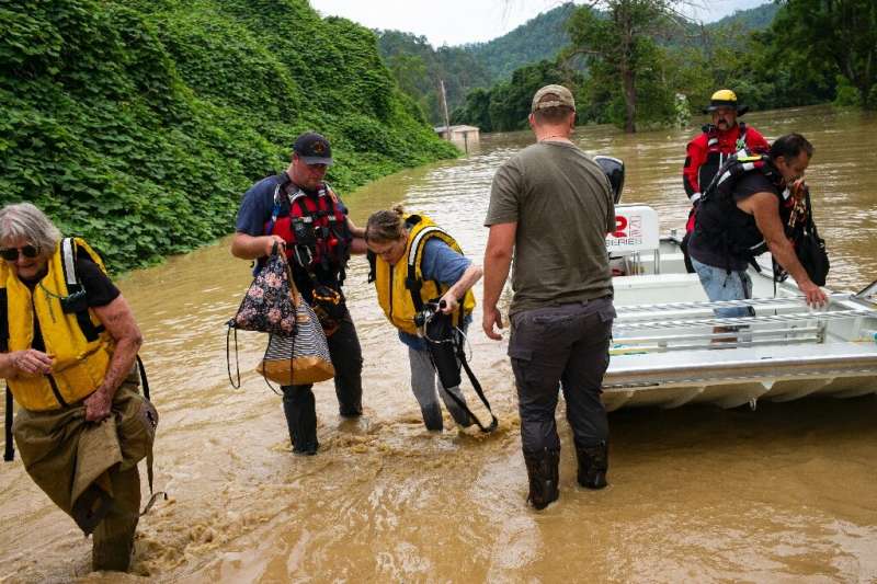 Members of a rescue team assist a family out of a boat in Quicksand, Kentucky, after flash floods