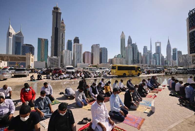 Muslim men perform Friday noon prayer in an area close to their workplace on the first working Friday in the Gulf emirate of Dub
