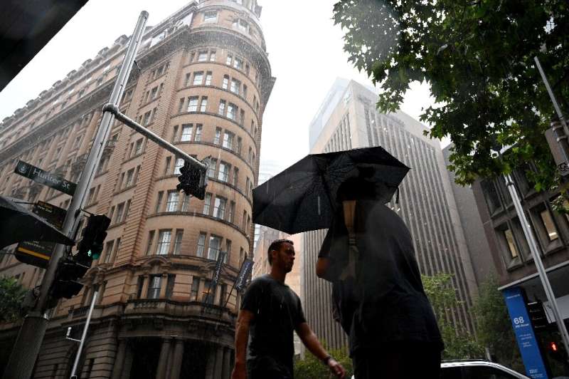 Pedestrians walk in heavy rain in the central business district of Sydney on February 22, 2022.