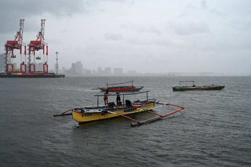 Люди охраняют свои лодки в Базеко, Манила, когда тайфун Нору приближается к Филиппинам.