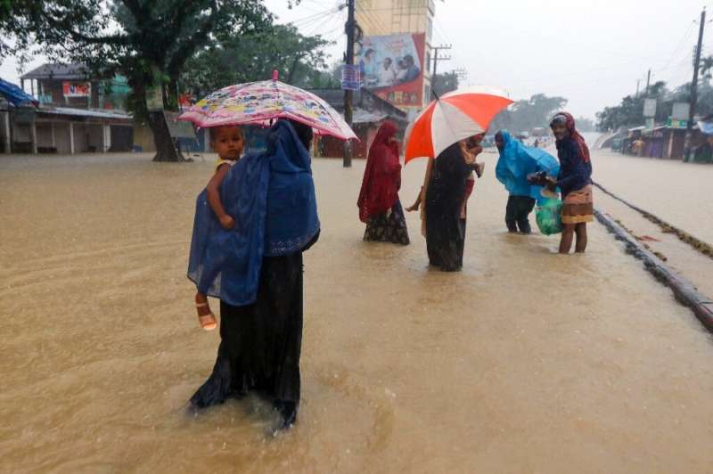 People walk on a flooded road after heavy monsoon rains in Sylhet, Bangladesh