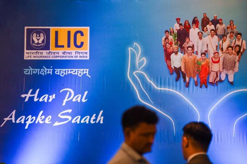 People walk past a promotional poster for the Life Insurance Corporation of India in Mumbai