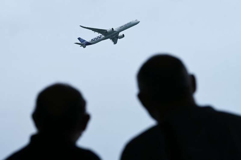 People watch as an Airbus A350 aircraft flies past at the Singapore Airshow on February 16, 2022