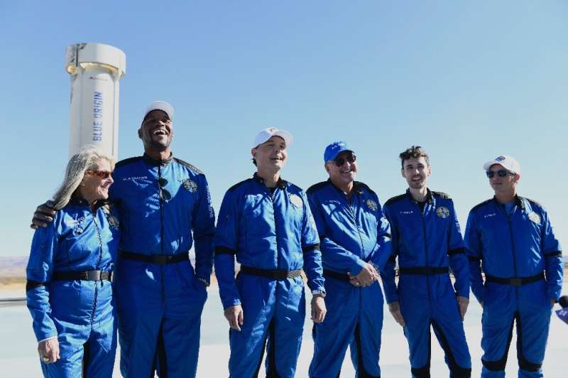 The Blue Origin NS-19 crew stand next to the New Shepard rocket after their successful launch on December 11, 2021