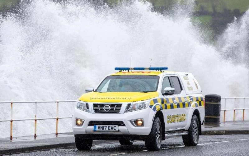 Waves crash over the sea wall as a coastguard vehicle keeps watch at Ballygally, Northern Ireland