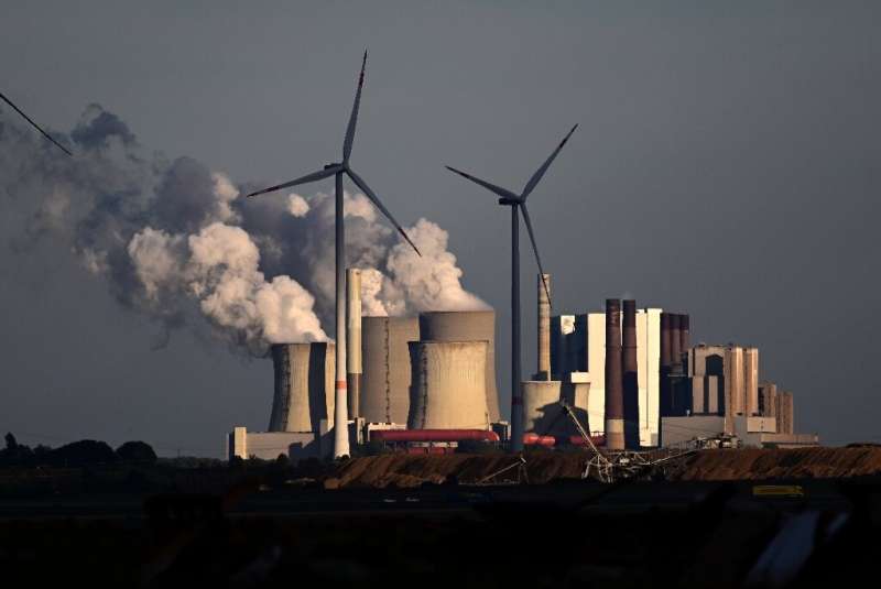 Ветряные турбины перед электростанцией, работающей на буром угле, недалеко от Нидераусема в западной Германии.